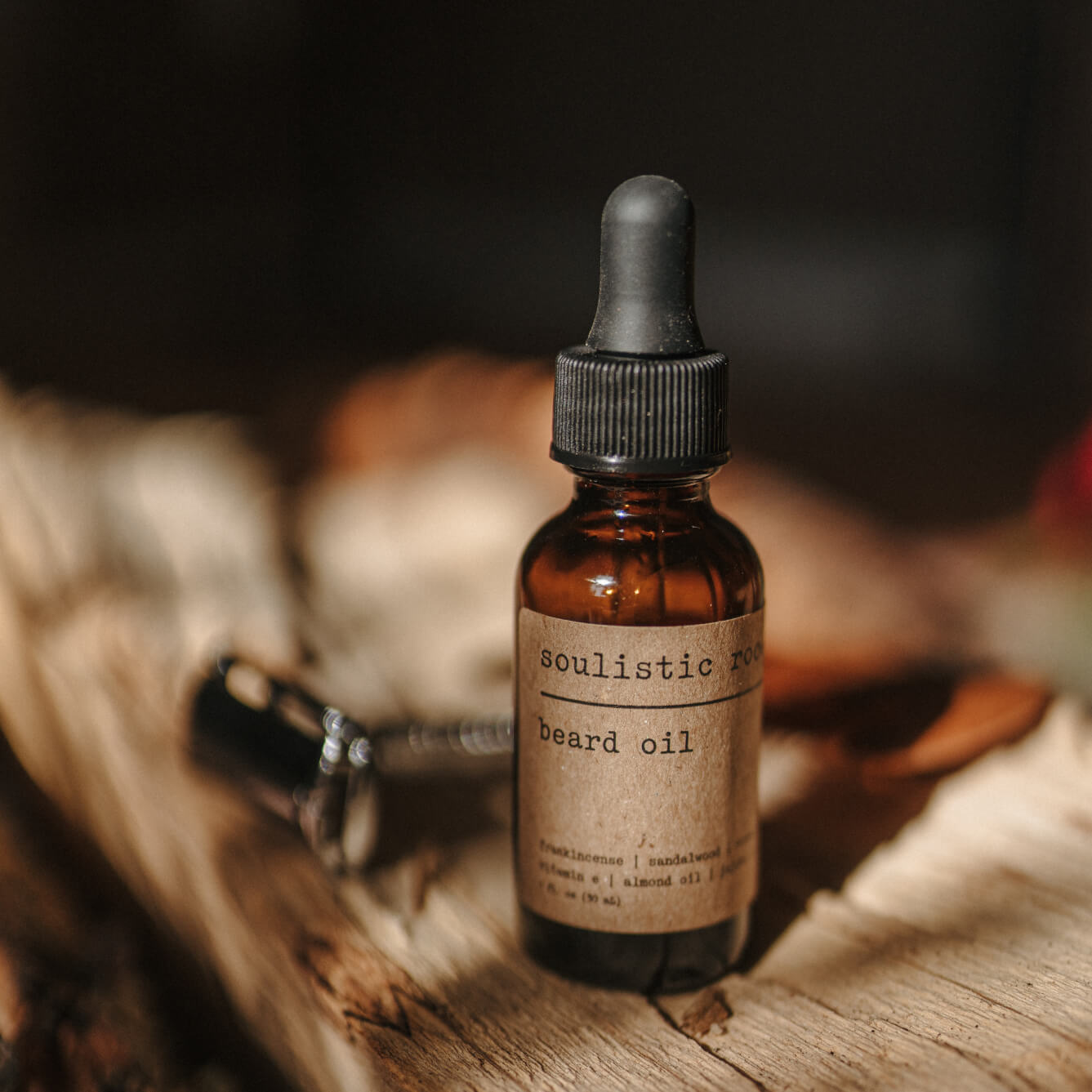 Bottle of Soulistic Root beard oil on a wooden surface with a razor in the background