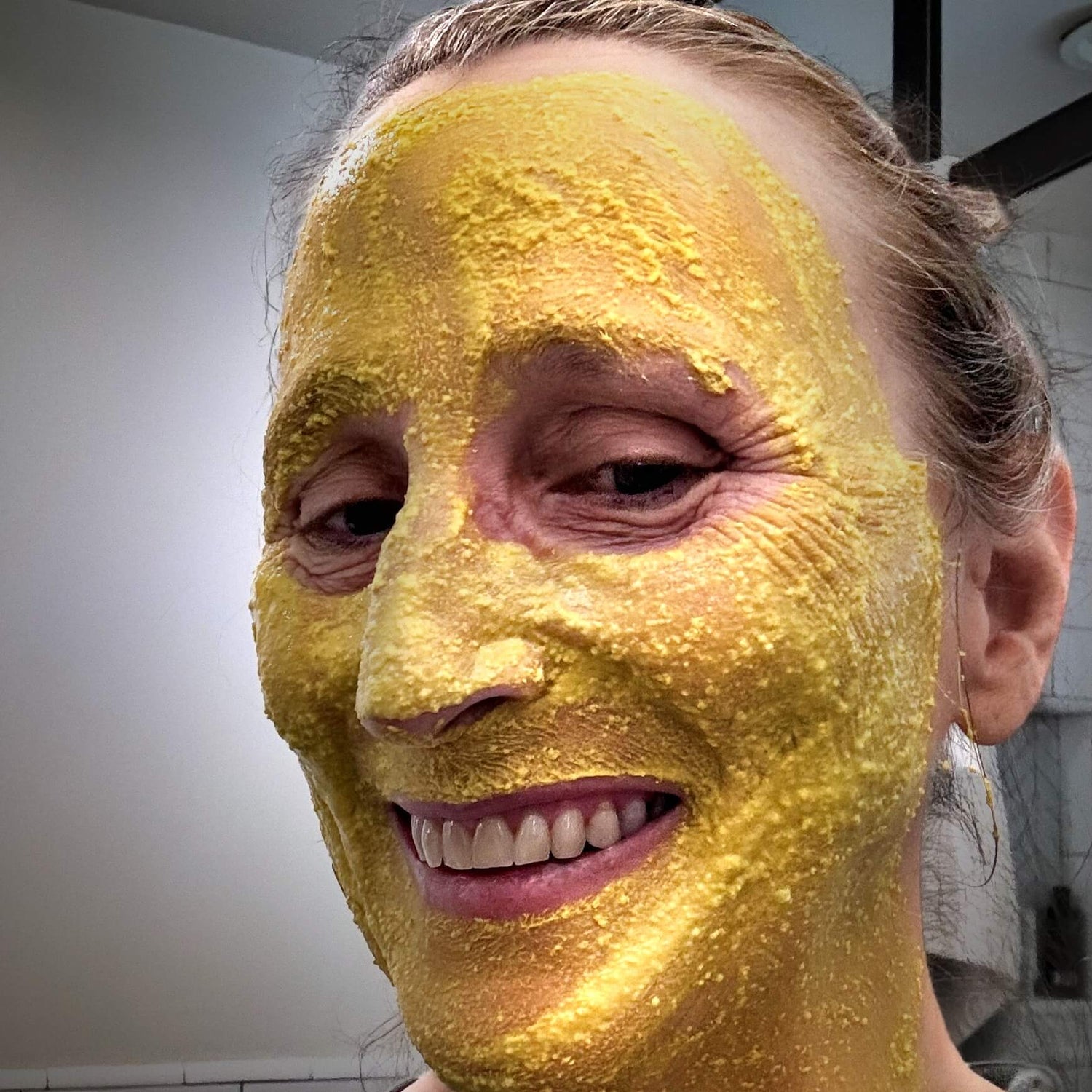 Woman with the bright yellow turmeric face mask applied