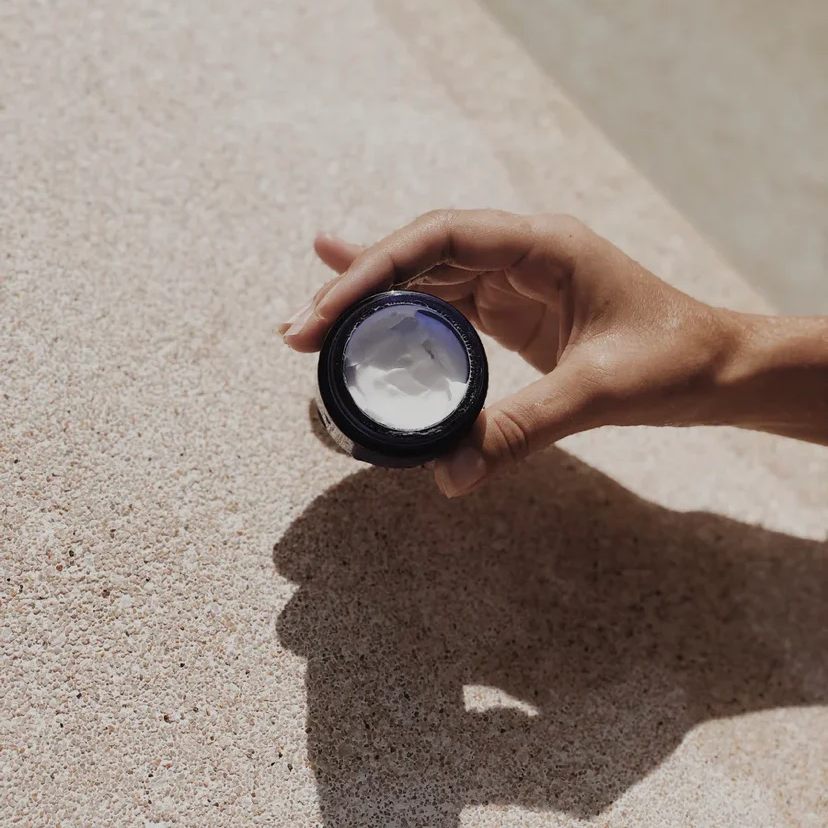 Woman holding open jar of the Tea Tree + Vitamin C Face Cream from Botanixx