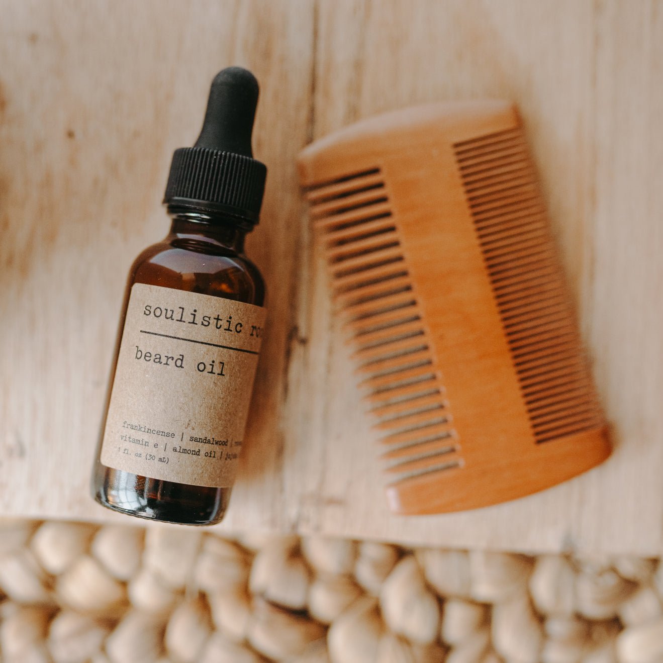 Bottle of Soulistic Root men's beard oil with a wooden comb on a wooden surface.