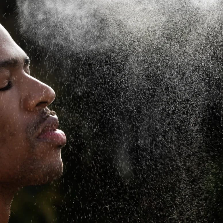 Person standing in a spray of MILO Hydrating Tonic