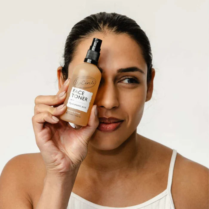 Woman holding a bottle of the Face Toner with Hyaluronic Acid from UpCircle Beauty.