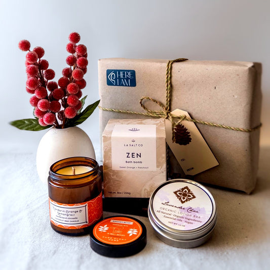 The Zen giftbox set with bath bomb, candle, and lotion bar in front of wrapped box with holiday decor.