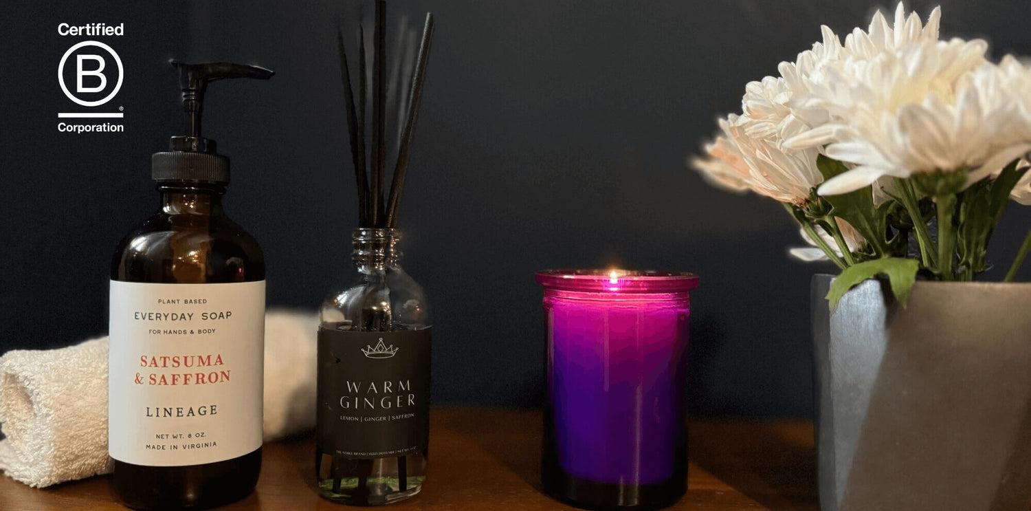 Hand soap, reed diffuser, aromatherapy candle, and a small planter on a desktop with a dark background