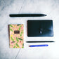 The mini notepad on a desk next to a wallet and pents