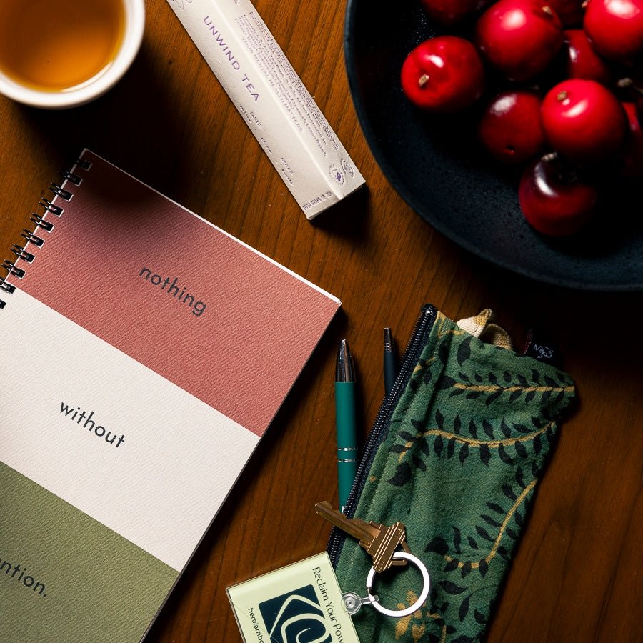 Table with notebook, pen case, cup of tea and a bowl of red apples