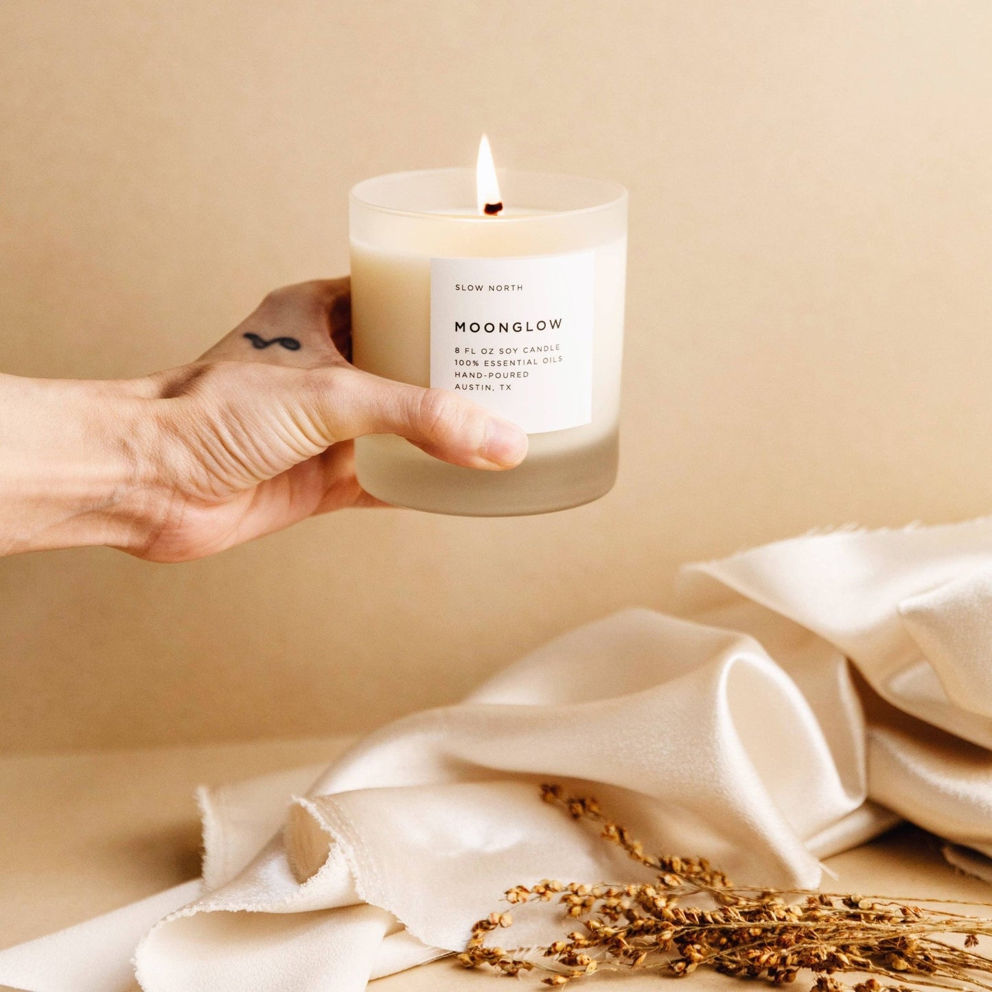 Hand holding the Moonglow essential oil candle over a cloth