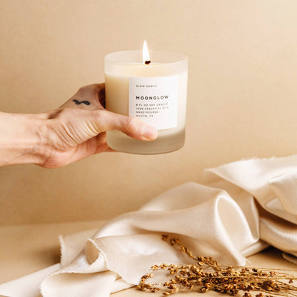 Hand holding the Moonglow essential oil candle over a cloth