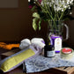 Selections from the Rejuvenation Box: eye pillow, lavender candle, body lotion, and saffron on table with flowers in background