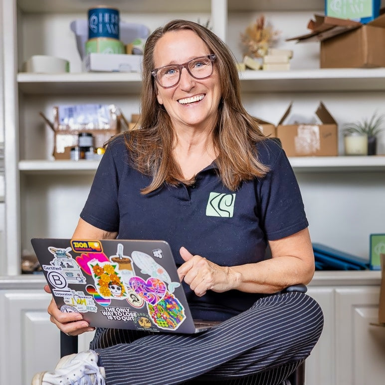 Renee with computer in front of products on shelves