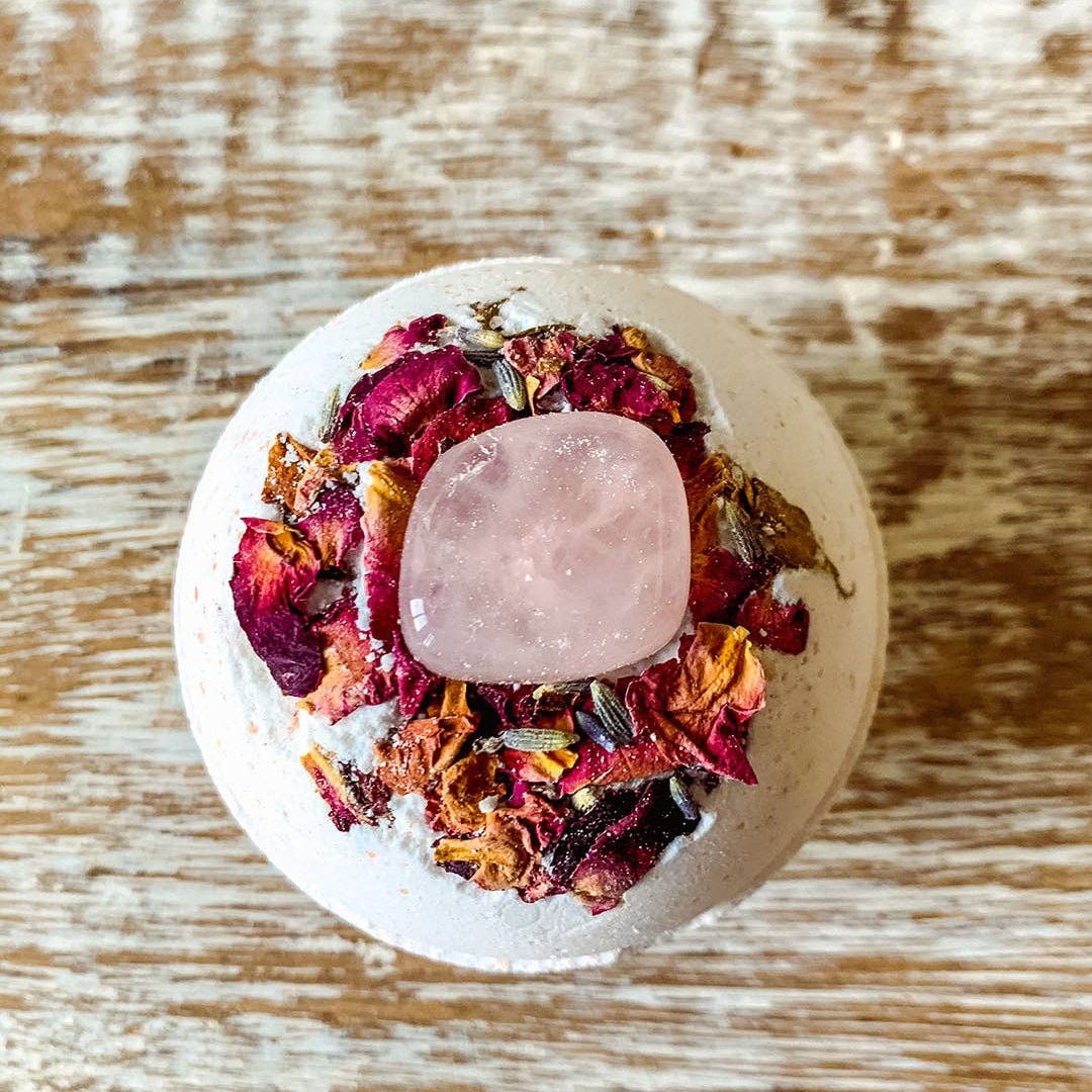 Rose Bath bomb with a pink crystal on top of a wooden surface