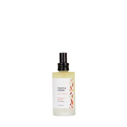 A bottle of aromatherapy room spray with Grapefruit and Jasmin from the Thistle Farms Love Heals collection in a frosted glass bottle for an uplifting experience.