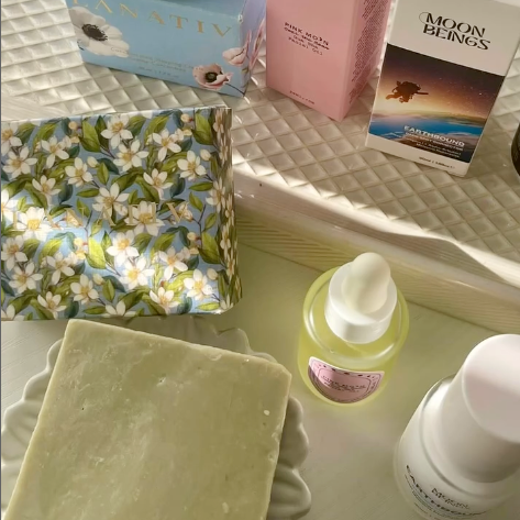 Cosmetic products including the Hawaiian Sandalwood bar of soap, bottles, and boxes on a textured surface.