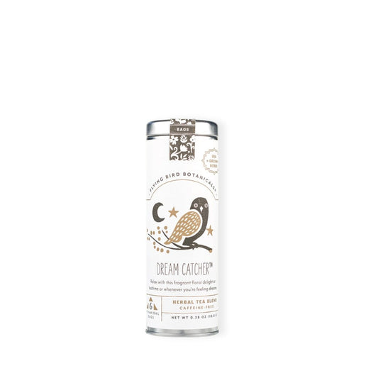 A tall cylindrical tin of Flying Bird Botanicals Dream Catcher Herbal Tea Blend Caffeine Free. Label features a white background with an owl and gold star illustration.