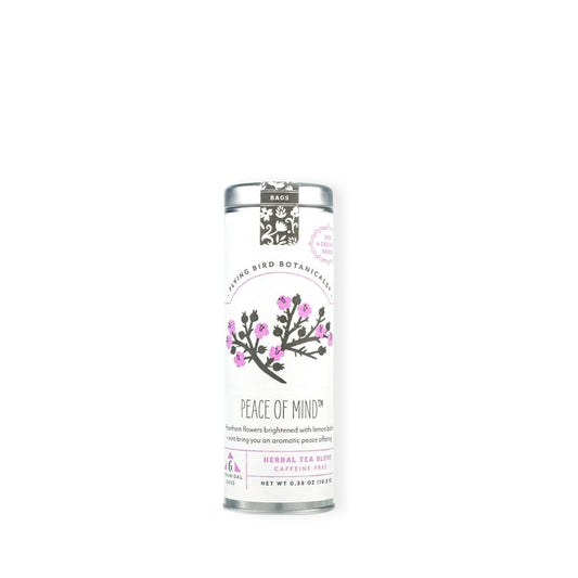 A tall, slim silver tin canister of Flying Bird Botanicals 'Peace of Mind' herbal tea, featuring a white label with pink flowers and black text, set against a plain white background.
