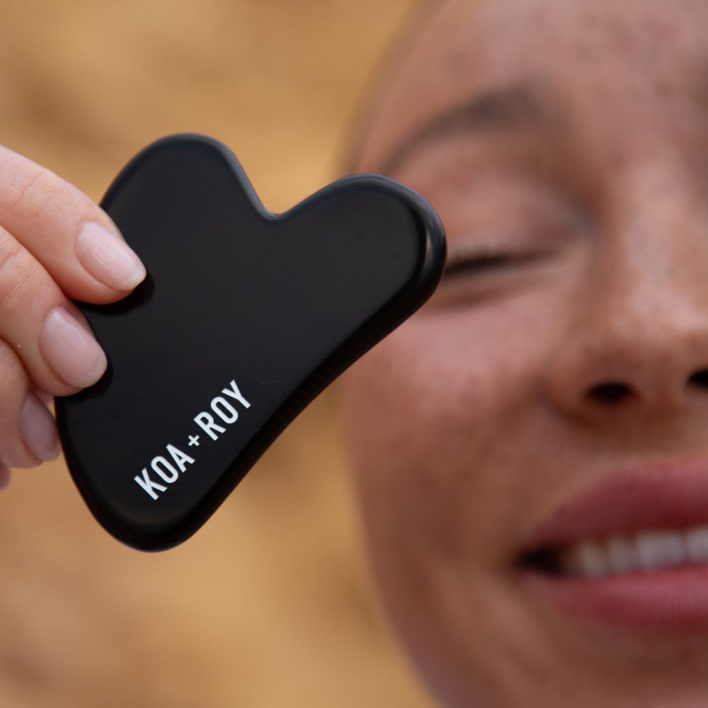 Woman holding a gua sha tool close to her face