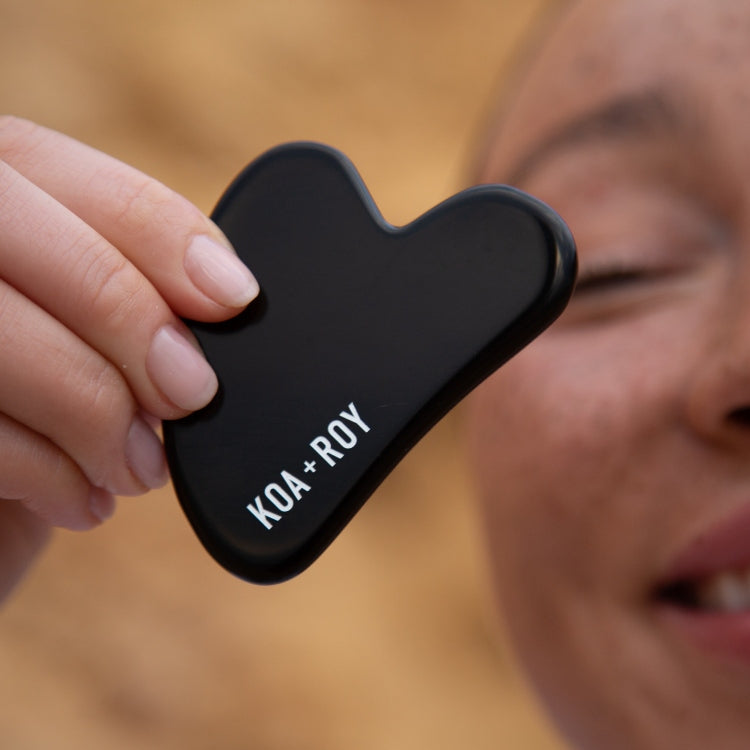 Woman holding a black Gua Sha from Koa + Roy