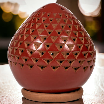 Rust colored geometric Luminary on a table with lights in the background